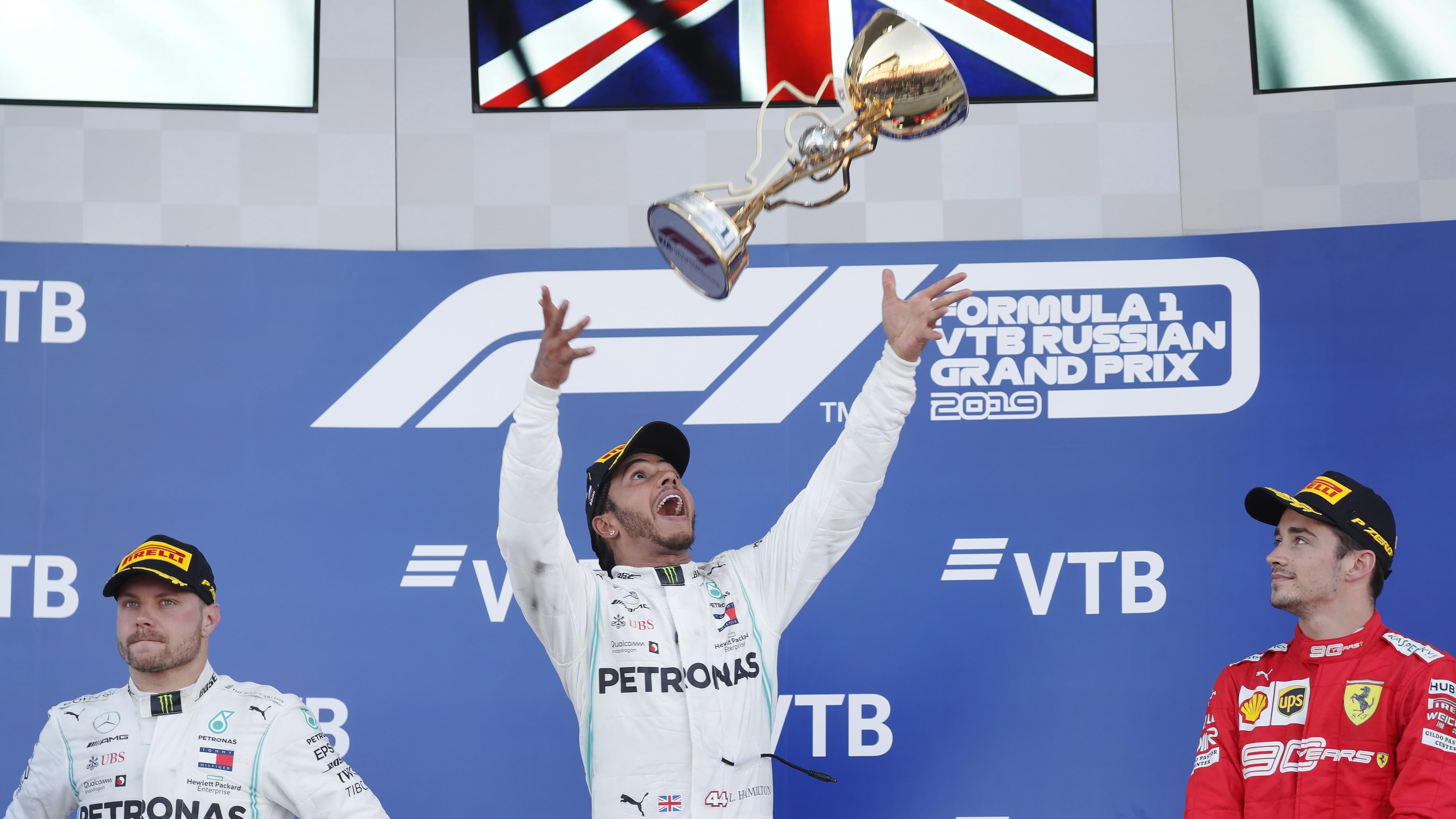 Hamilton festeja lanzando su copa al aire.