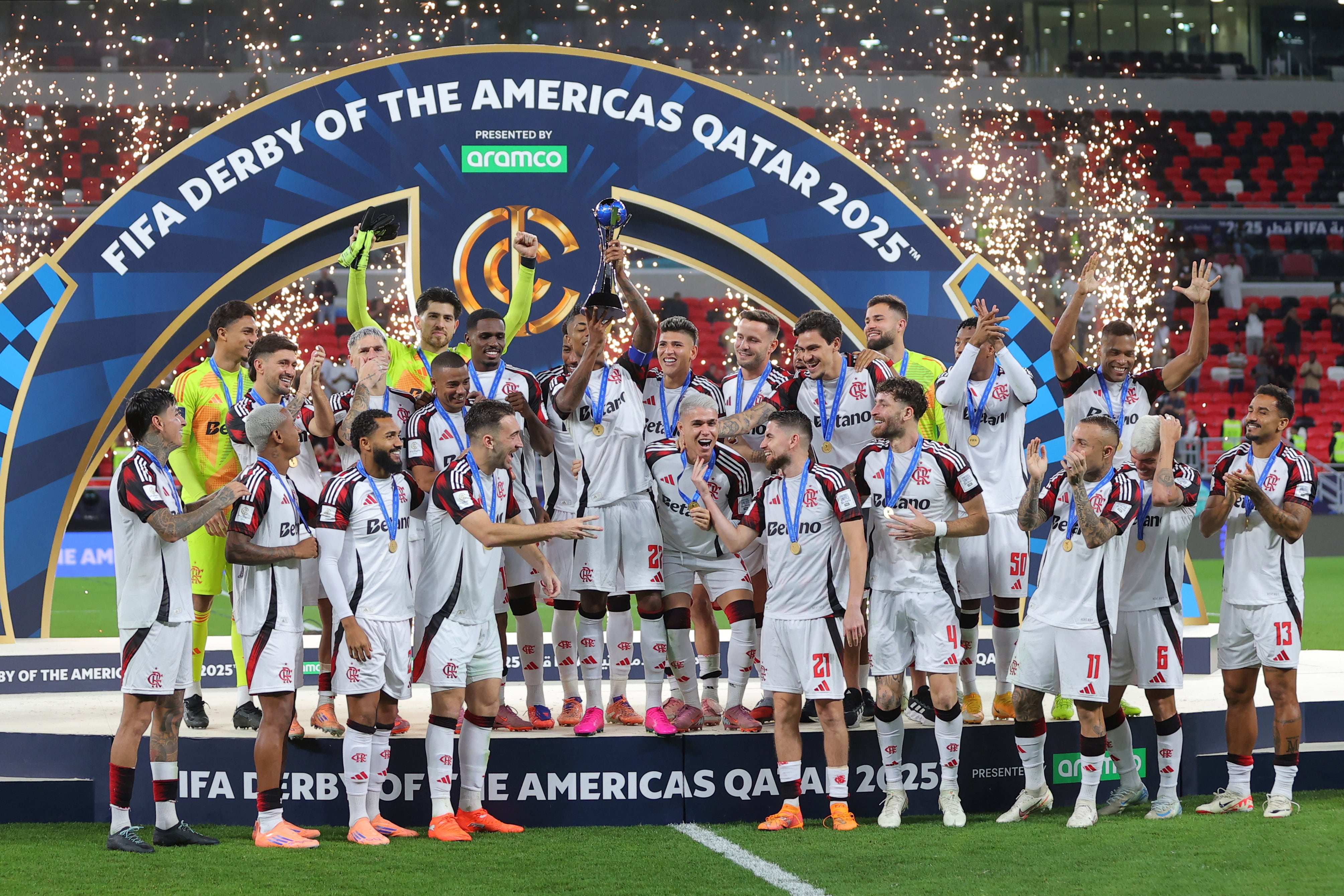 Flamengo's Bruno Henrique lifts the trophy as he celebrates with teammates after wining the FIFA Derby of the Americas match between Cruz Azul and Flamengo at Ahmad Bin Ali Stadium in Doha on December 10, 2025. (Photo by Karim JAAFAR / AFP)
