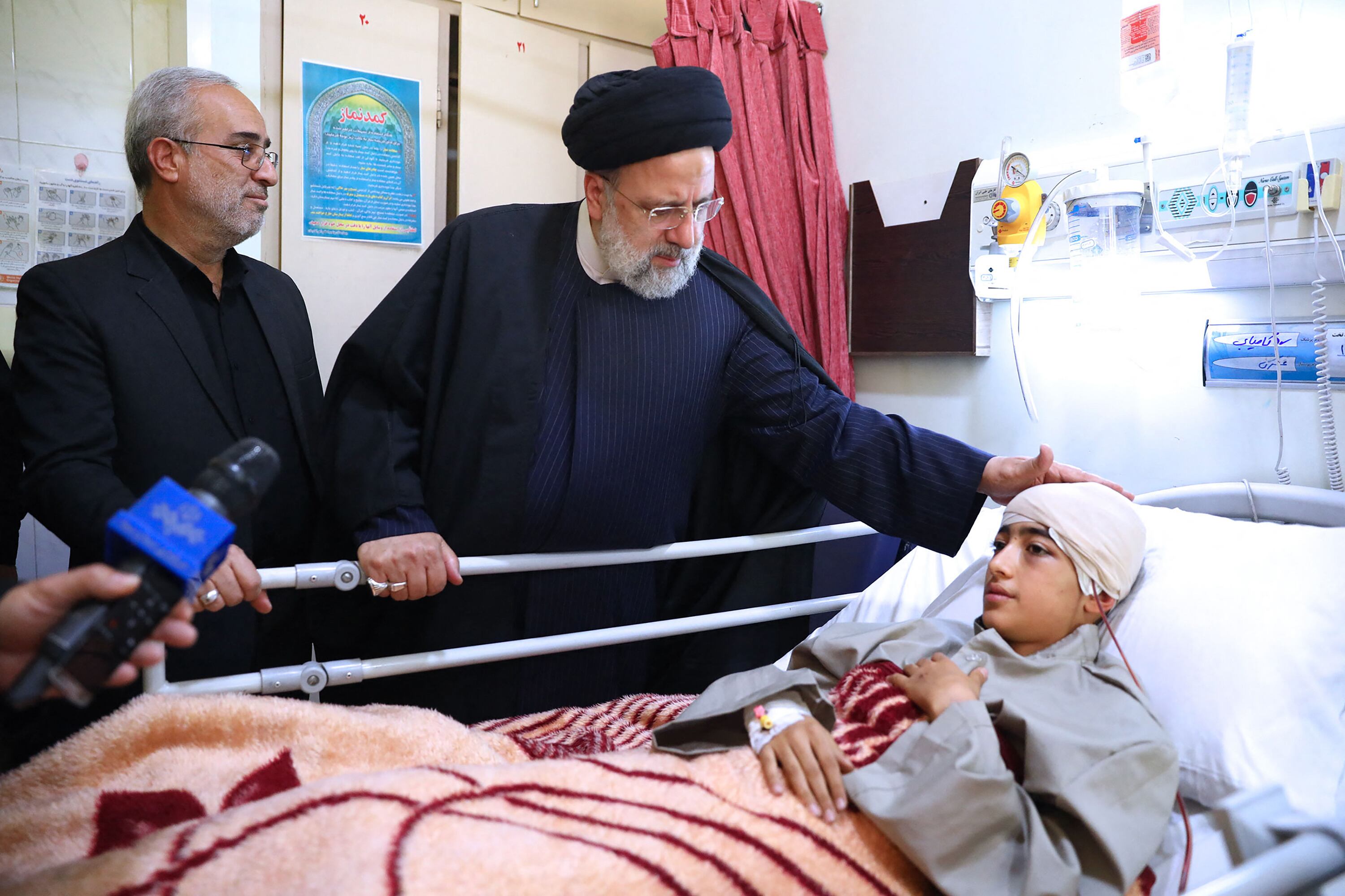 El Presidente Irán, Ebrahim Raisi, junto a un herido en atentado. 