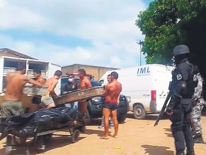 Reclusos cargan cadáveres en vehículos después de la masacre de Roraima.