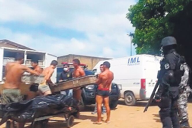 Reclusos cargan cadáveres en vehículos después de la masacre de Roraima.