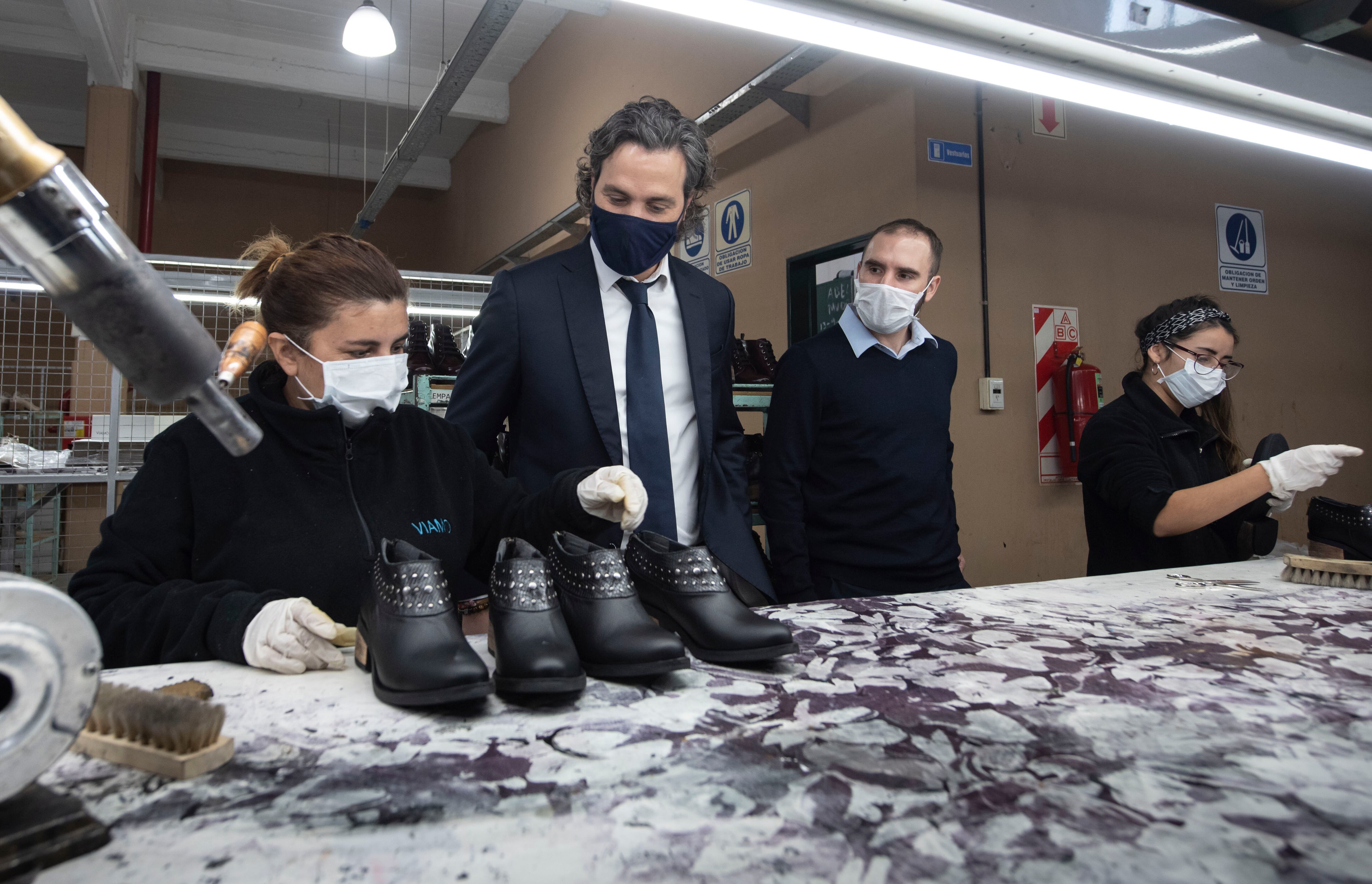 Una empleada les muestra a Santiago Cafiero y Martín Guzmán cómo es el proceso de control de calidad previo al empaquetado.