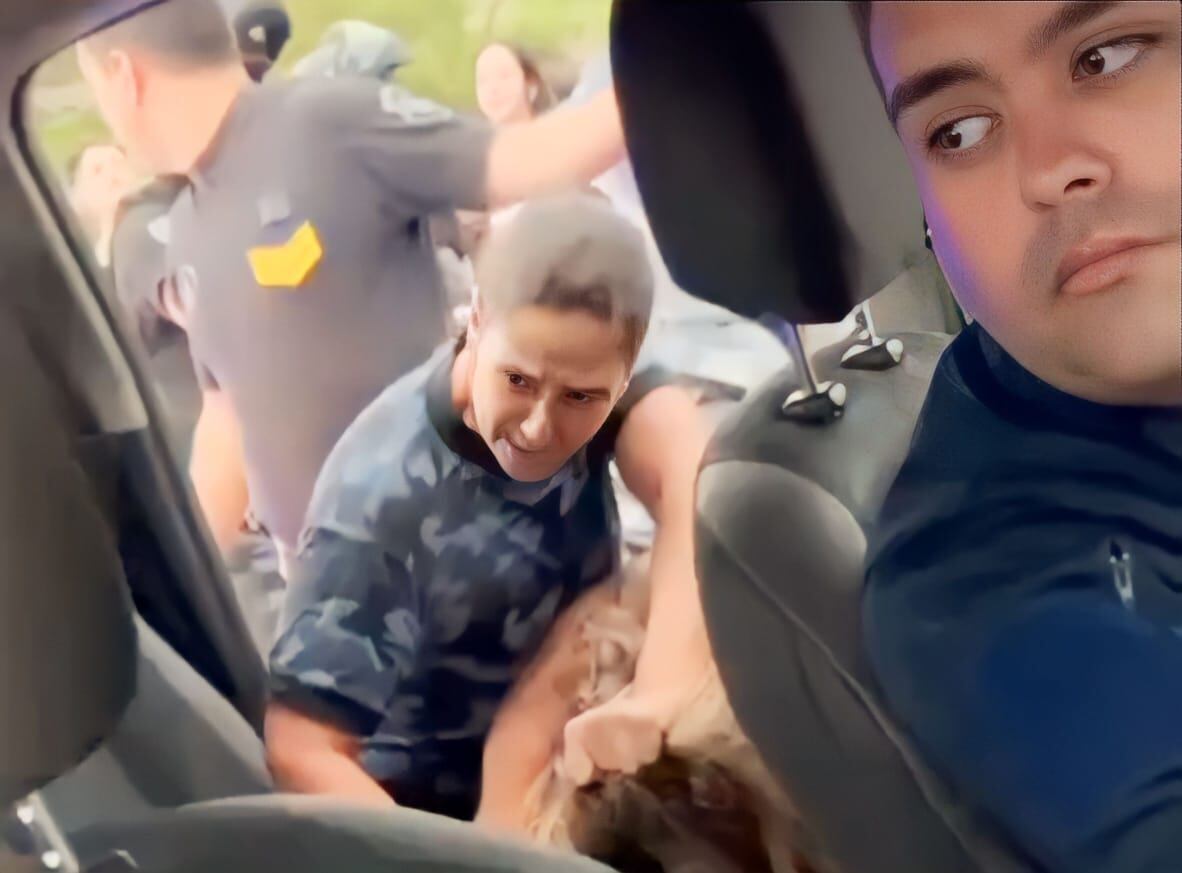 La agente policial entrando de los pelos a la joven al móvil.