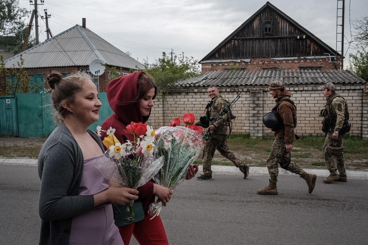 Mujeres con flores y soldados armados se cruzan en Raihodorok, Ucrania. 