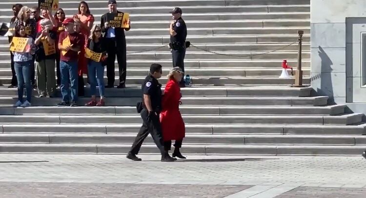 Fonda, llevada por un oficial, con la smanos atadas, durante la protesta en Washington.