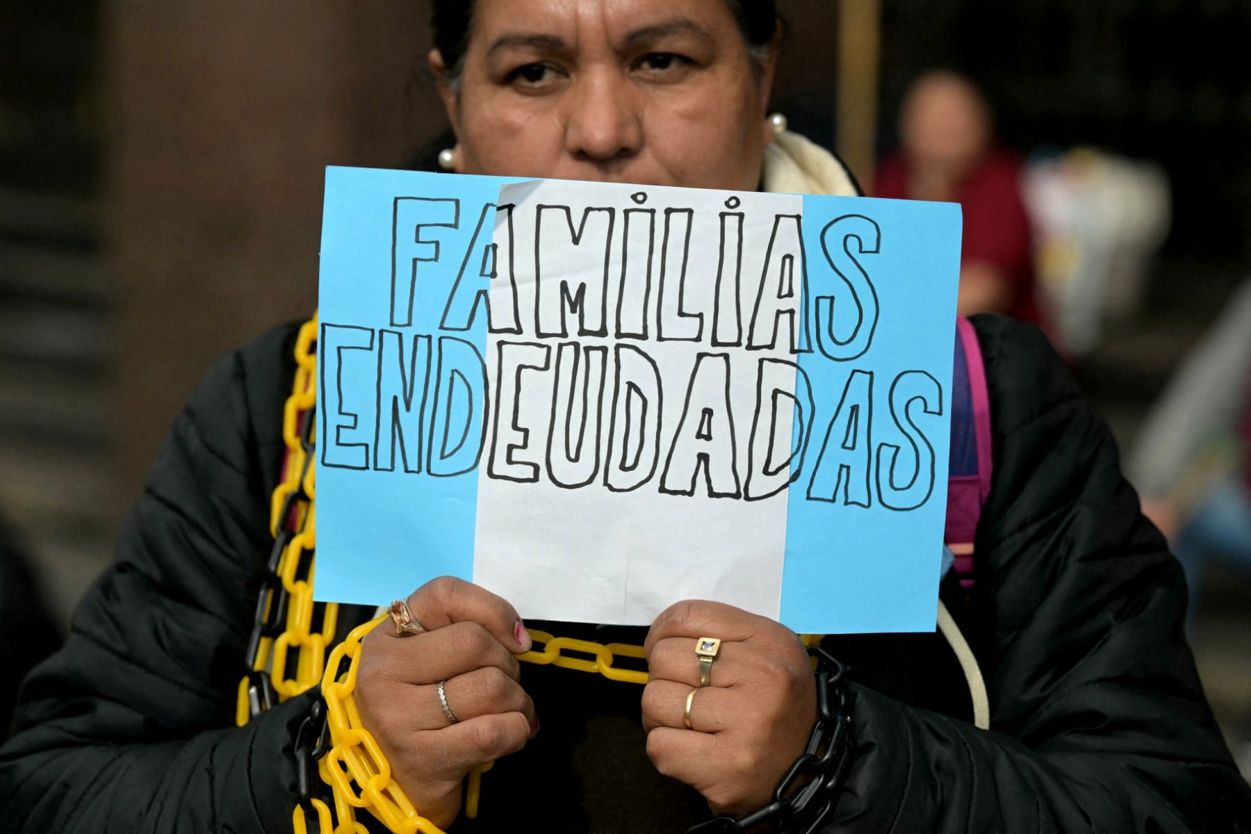 A member of the political group Libres del Sur holds a sign reading "Indebted families" during a protest against Mercado Libre creator Marcos Galperin due the usurious interest rates over debts of impoverished users within the government of Argentina's President Javier Mile