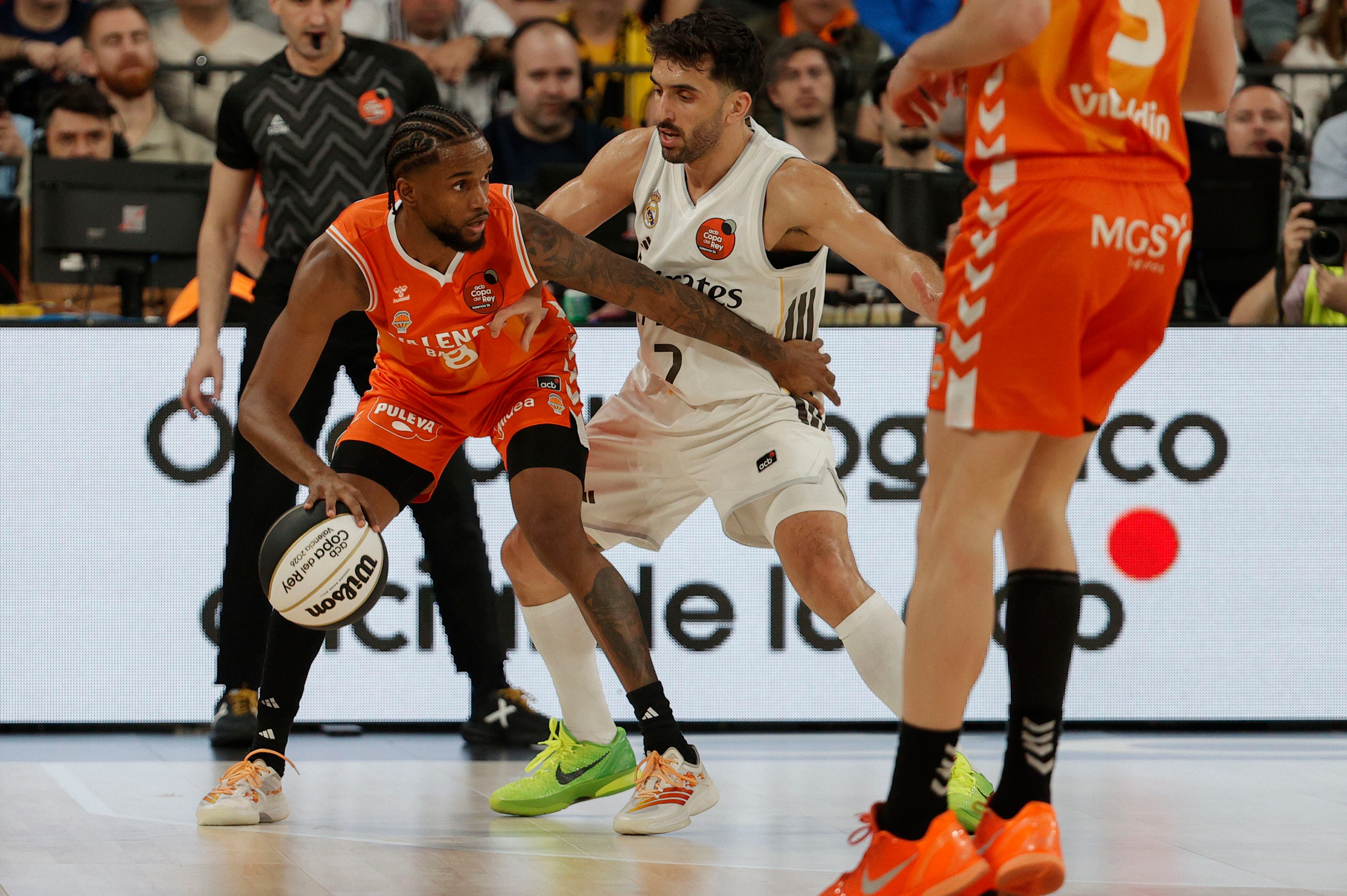 VALENCIA, 21/02/2026.- El base dominicano del Valencia Basket Jean Montero (i) lucha con Facundo Campazzo, del Real Madrid, durante el partido de semifinales de la Copa del Rey de Baloncesto que Valencia Basket y Real Madrid disputan este sábado en el Roig Arena, en Valencia. EFE/ Manuel Bruque