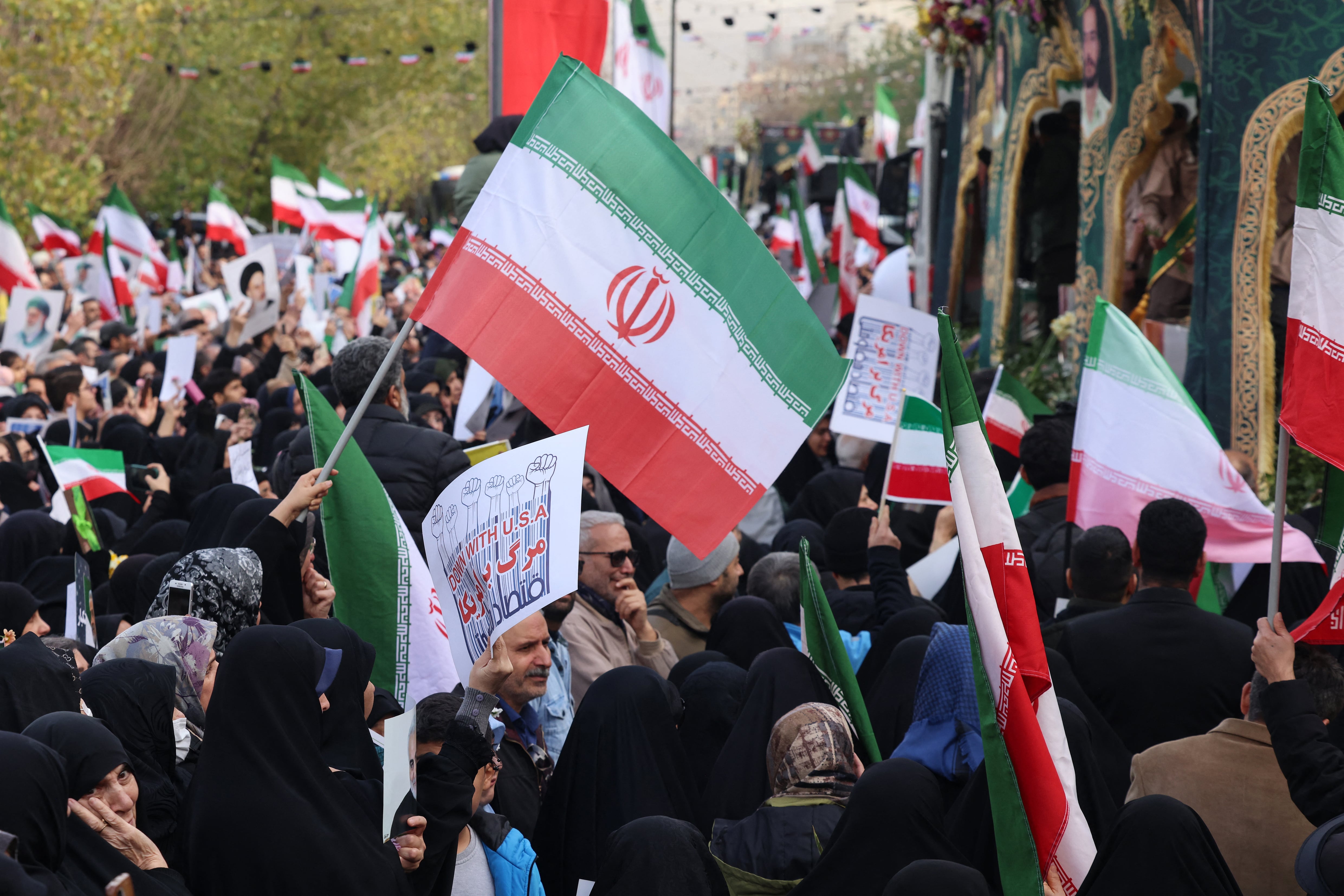 Iranians wave national flags during the funerals of security forces personnel killed in recent protests in Tehran on January 14, 2026. A funeral ceremony began in Tehran on January 14, 2026 for over 100 members of the security forces and other "martyrs" killed in the wave of protests that has rocked the Islamic republic, state television said. (Photo by ATTA KENARE / AFP)