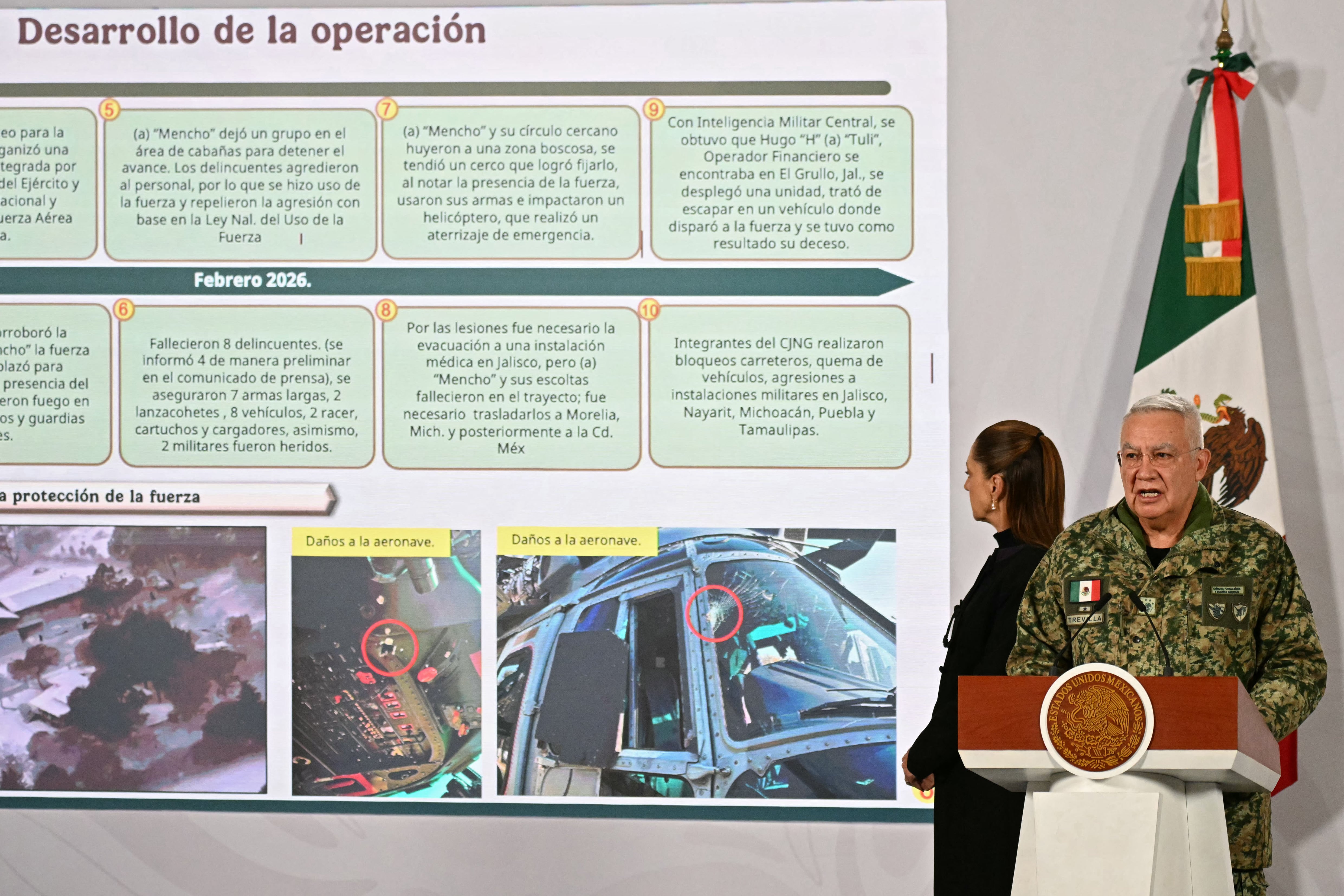 Mexico's Minister of Defence Ricardo Trevilla Trejo speaks next to President Claudia Sheinbaum during her daily press conference at the Palacio Nacional in Mexico City on February 23, 2026. Mexico was on high alert on February 23 with schools closed and travelers stranded, as members of a powerful drug cartel went on a violent rampage across parts of the country after the army announced it had killed its leader. (Photo by YURI CORTEZ / AFP)