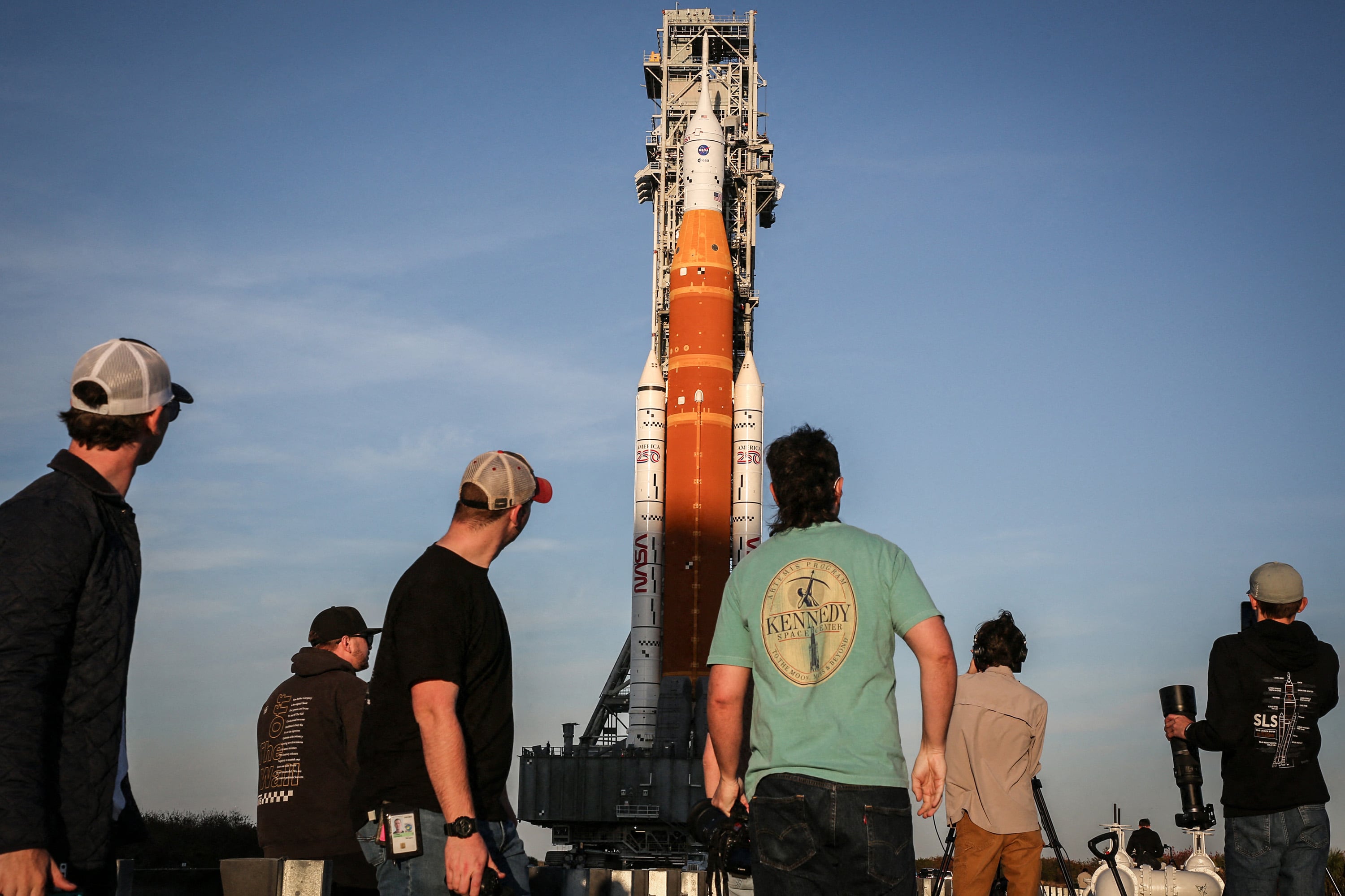 Members of the media look on as the mobile launcher 1 containing the massive Artemis II Space Launch System (SLS)