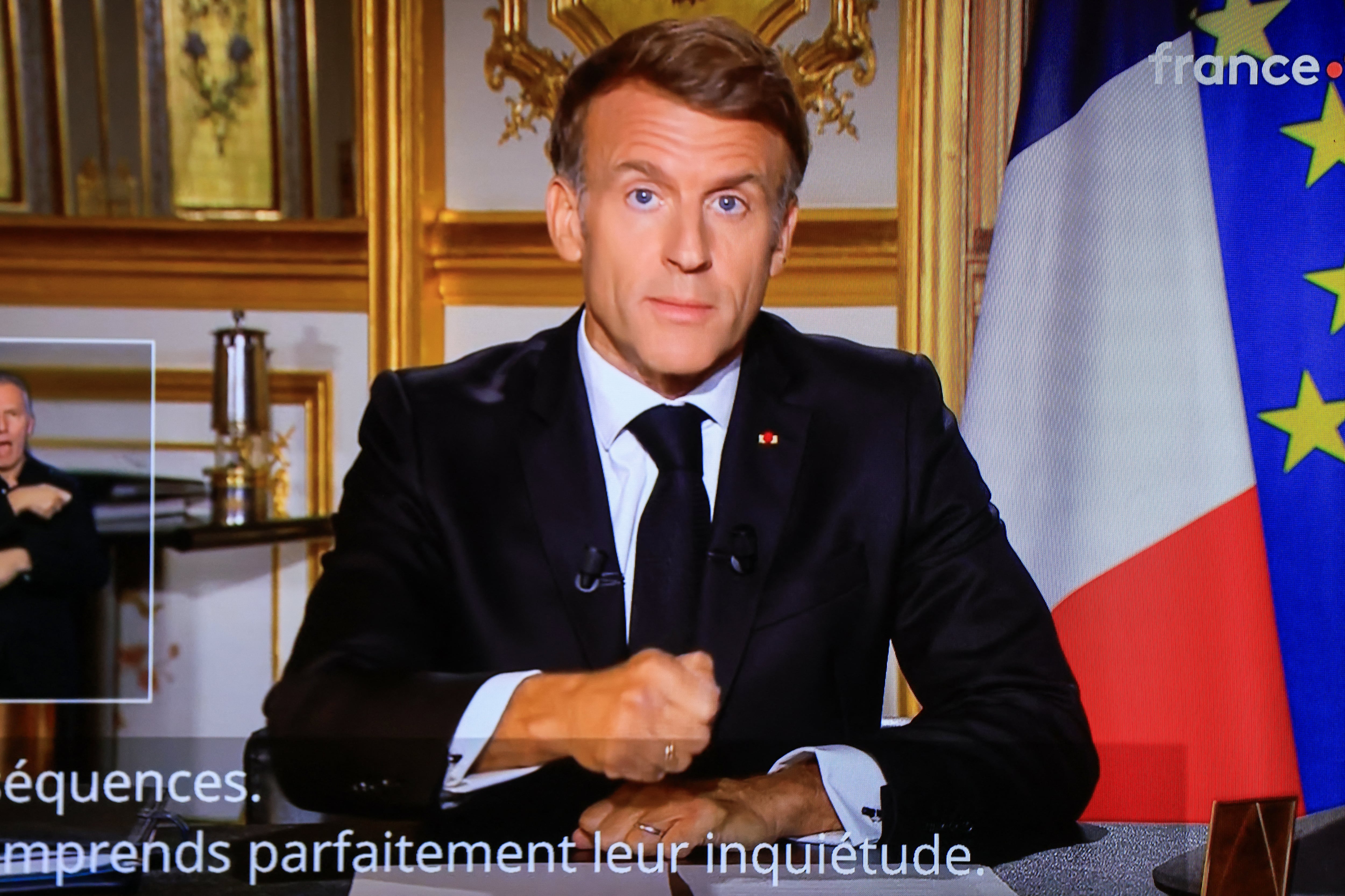 This photograph shows a television monitor broadcasting France's President Emmanuel Macron giving a speech from the Elysee Presidential Palace