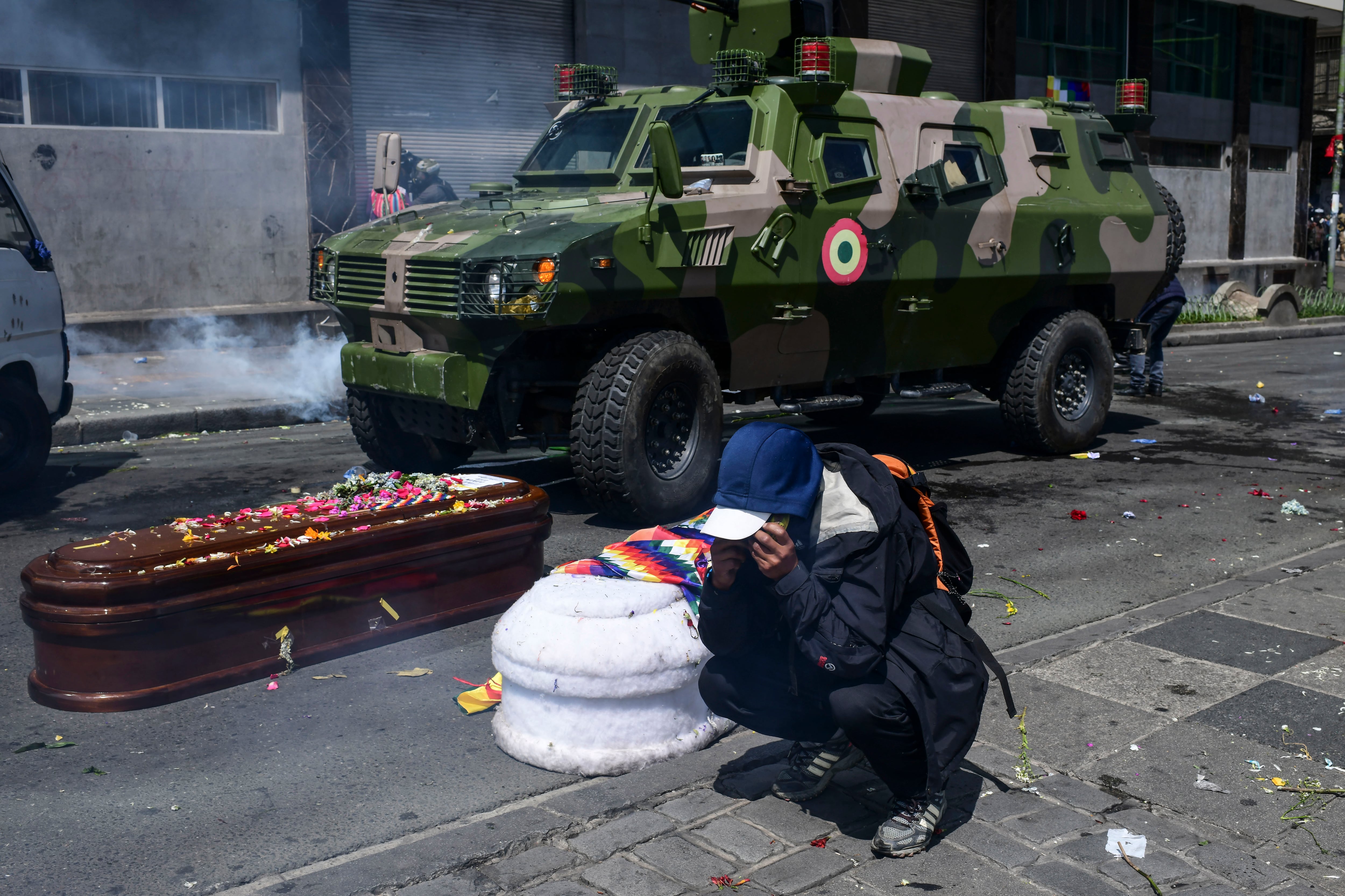 Un manifestante junto a los féretros en medio de la represión.