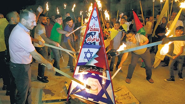 Palestinos queman una figura con la bandera de Israel y la imagen del rey de Baréin en Hebron, Cisjordania.