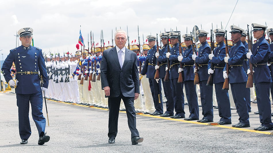 El presidente de facto Michel Temer inspecciona tropas en el aeropuerto al llegar a una reunión del Consejo Militar de Defensa en Brasilia.
