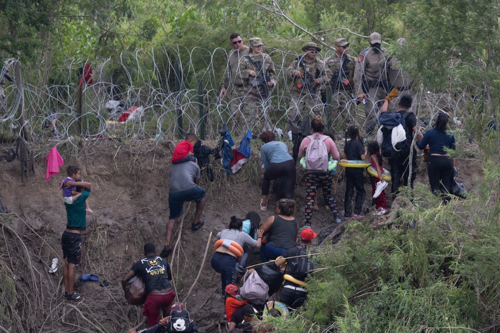 Imigrantes enfrentan a guadrias fronterizos de EE.UU. tras cruzar el Río Grande en Matamoros, México.