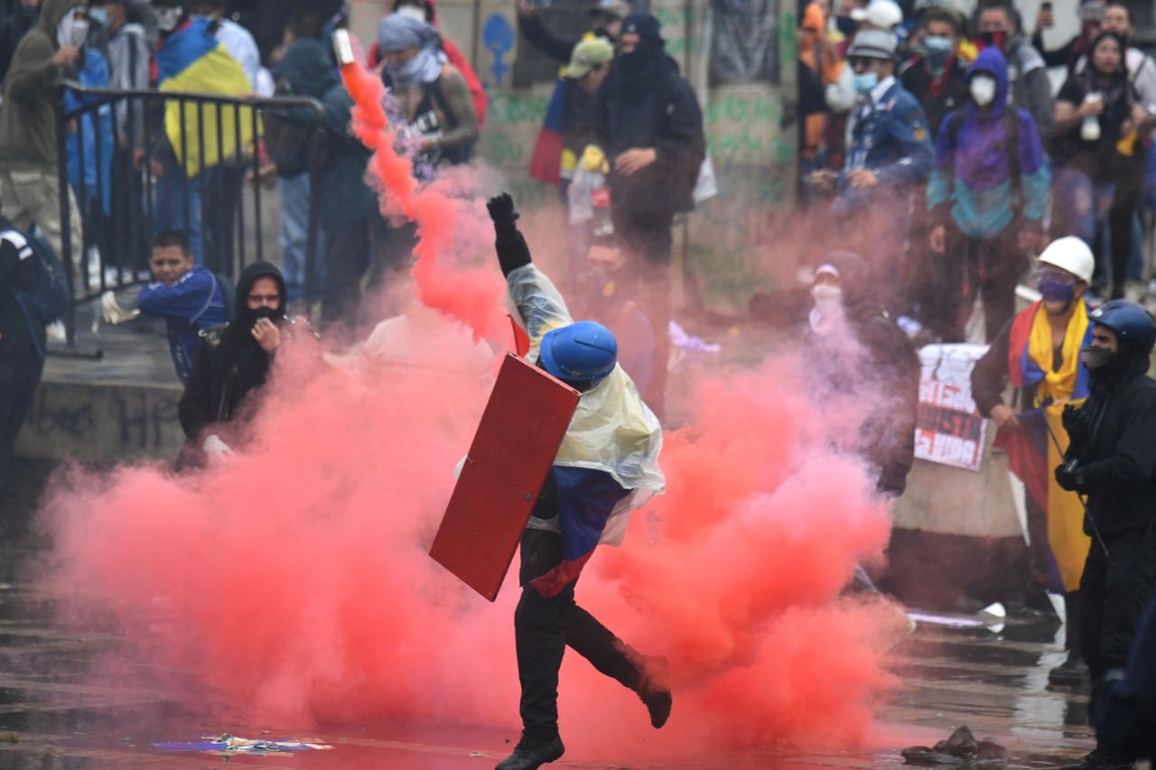 Un manifestante arroja una bomba de humo durante una protesta en Bogotá