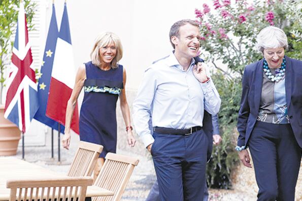 Macron, ayer, entre su esposa Brigitte (izq.) y May.