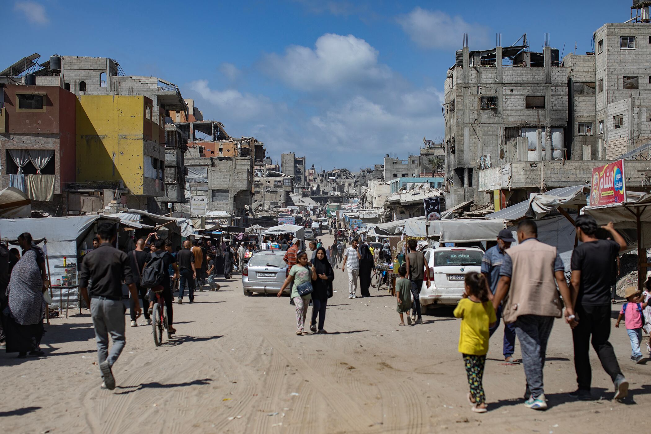 Mientras Hamas evalúa el plan de Trump, gazatíes caminan junto a edificios destruidos en una calle de Jan Yunis