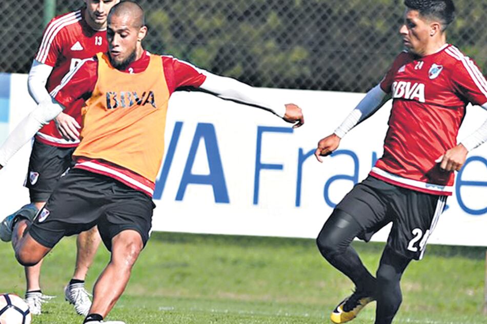 n Jonatan Maidana le pega a la pelota en el entrenamiento de ayer, mientras Enzo Pérez intenta controlarlo.