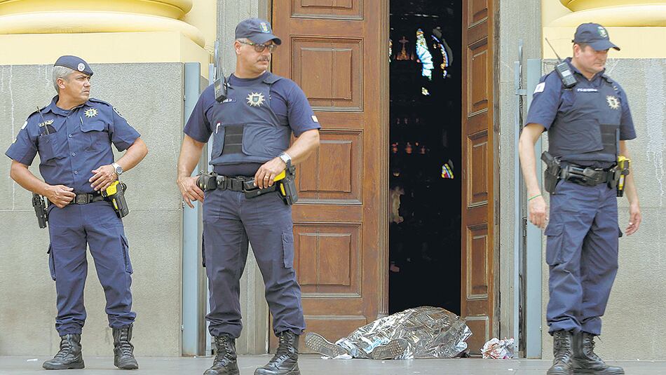 Agentes municipales custodian un cadáver en la entrada a la catedral de Campinas, cerca de San Pablo.