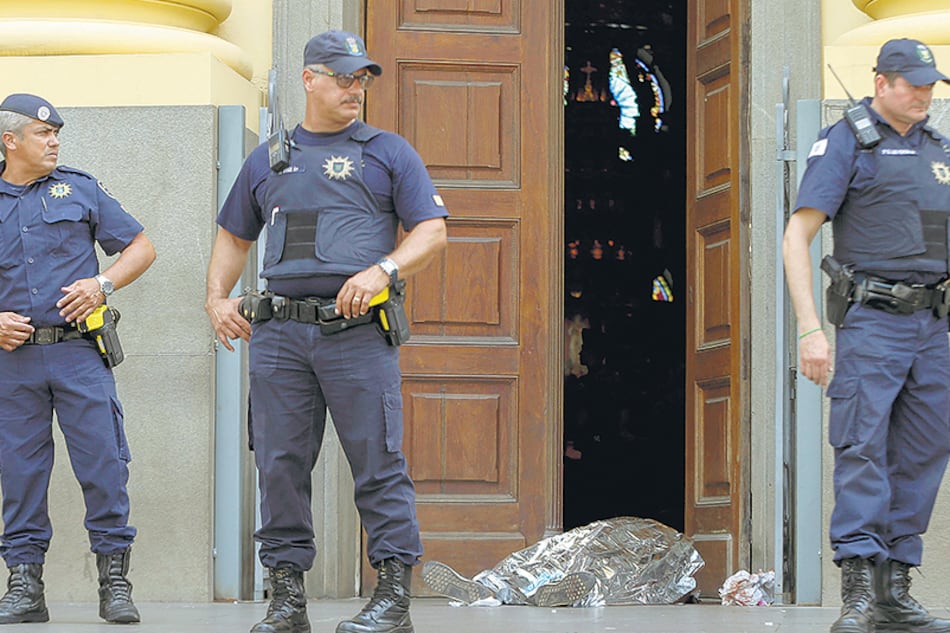 Agentes municipales custodian un cadáver en la entrada a la catedral de Campinas, cerca de San Pablo.