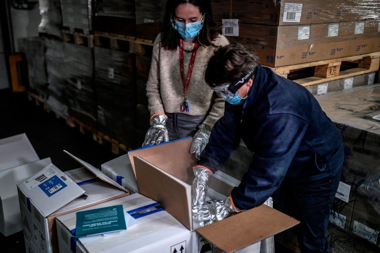 Trabajadores de salud abren las primeras cajas de vacunas Pfizer en una farmacia mayorista cerca de París