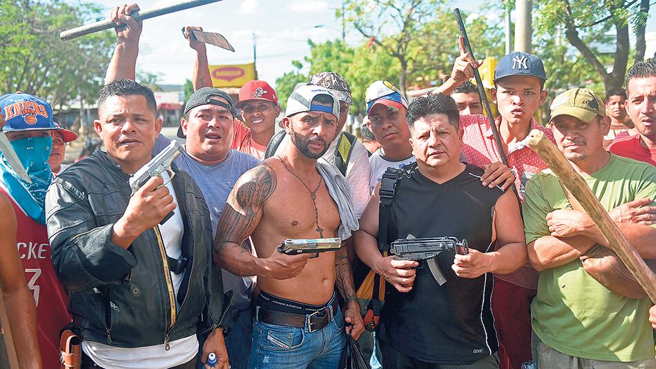 Los dueños de un supermercado de Managua protegen con sus armas su negocio de los saqueos.