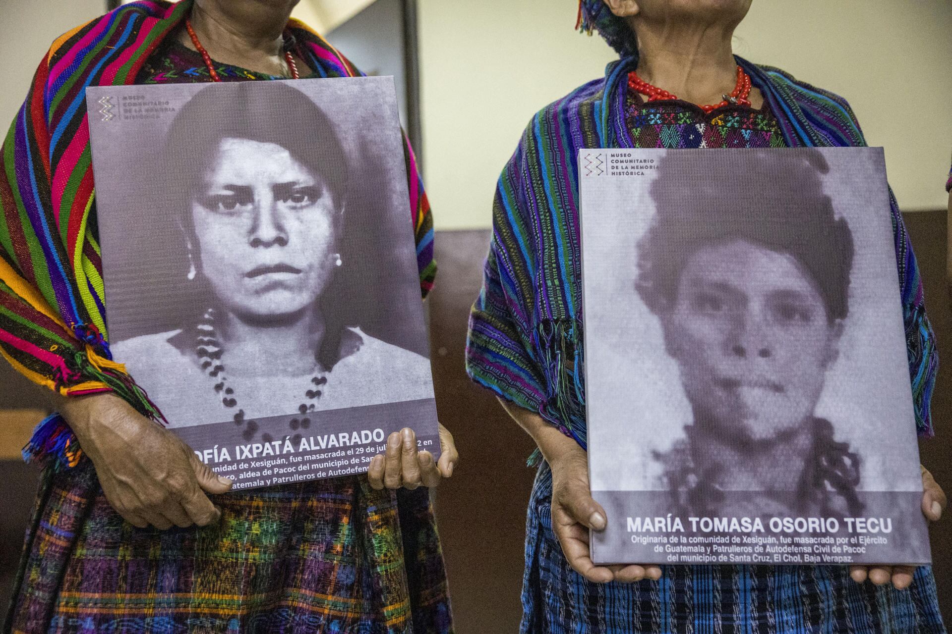 Paulina Ixpatá y Máxima Garcia, sobrevivientes de la masacre del Rancho Bejuco posan con el retrato de sus familiares masacradas.