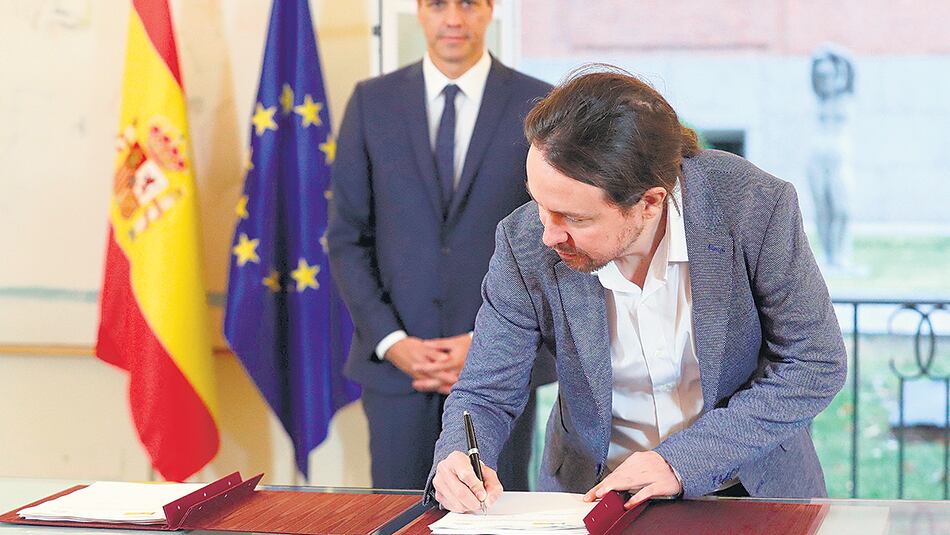 Iglesias firma el acuerdo bajo la atenta mirada de Sánchez ayer en Madrid.