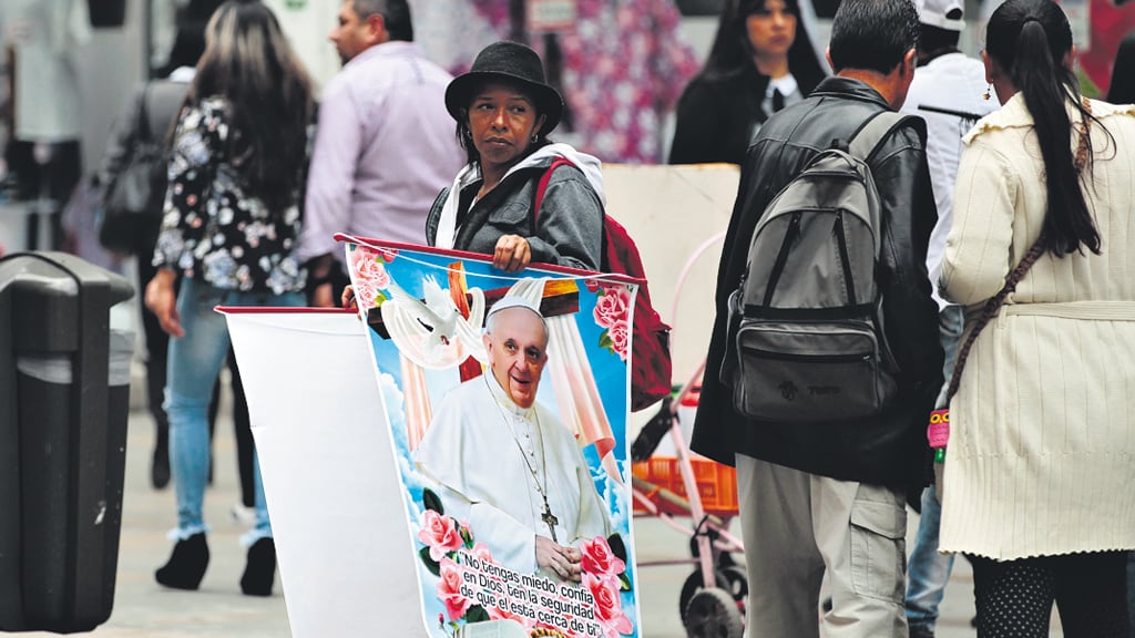Una mujer vende afiches con la cara del Papa ayer cerca de la catedral de Bogotá.