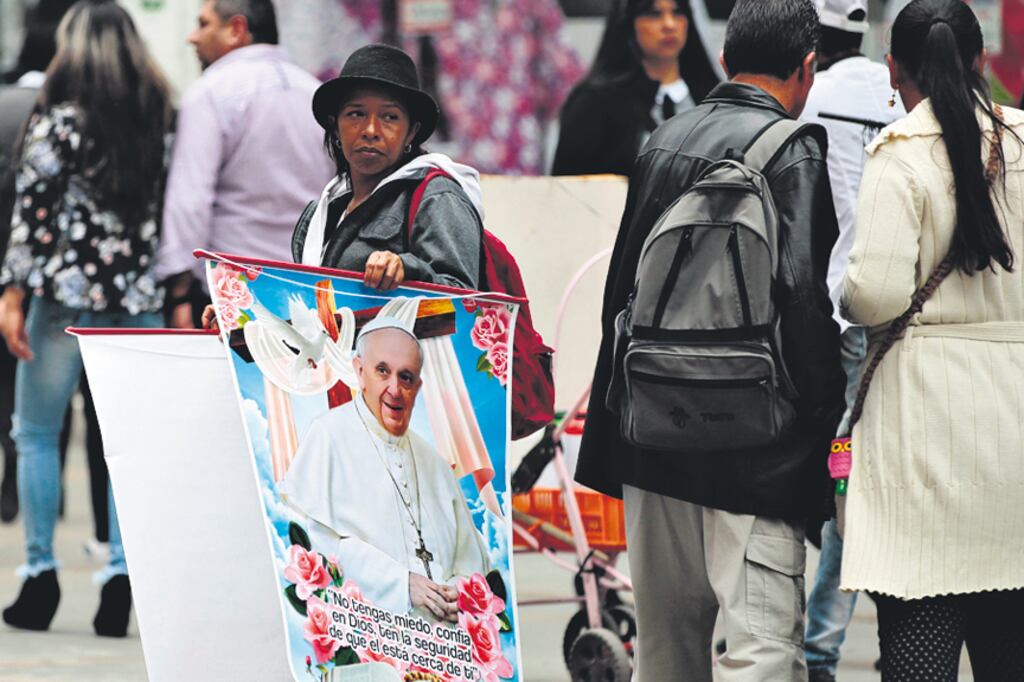 Una mujer vende afiches con la cara del Papa ayer cerca de la catedral de Bogotá.