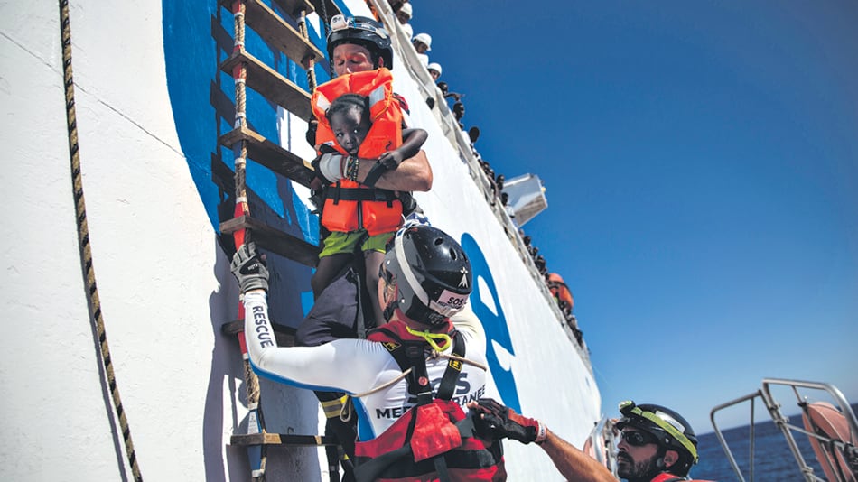 Voluntarios sostienen a una niña rescatada a 20 kilómetros de la costa de Libia.