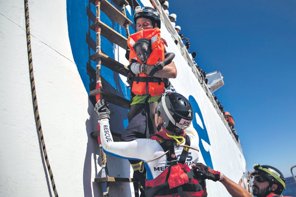 Voluntarios sostienen a una niña rescatada a 20 kilómetros de la costa de Libia.