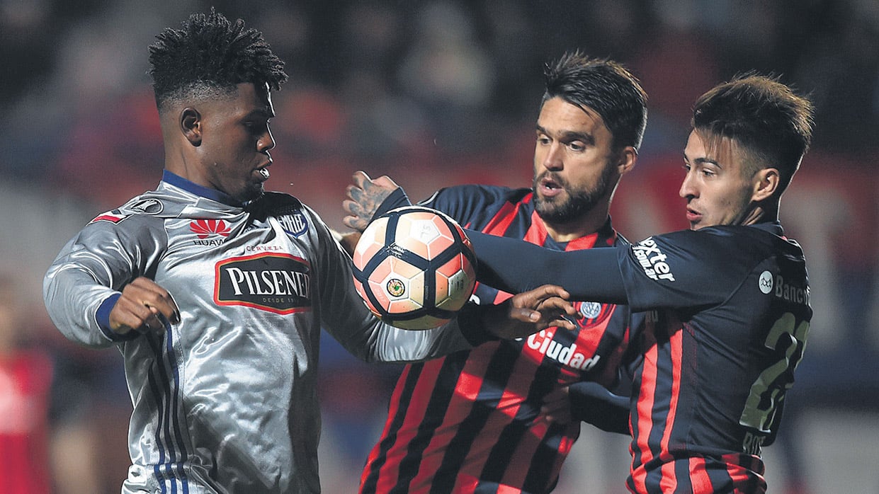 Rojas y Caruzzo intentan frenar a De Jesús.