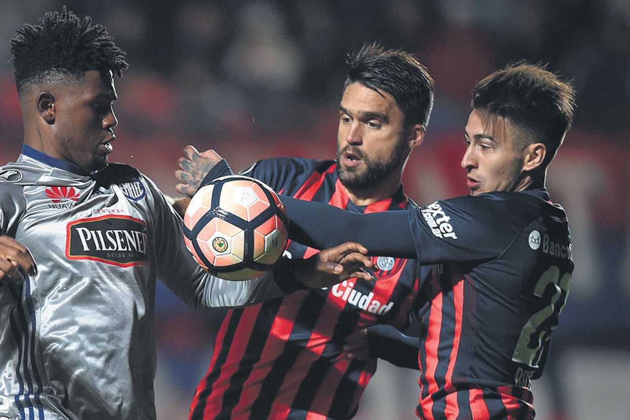 Rojas y Caruzzo intentan frenar a De Jesús.