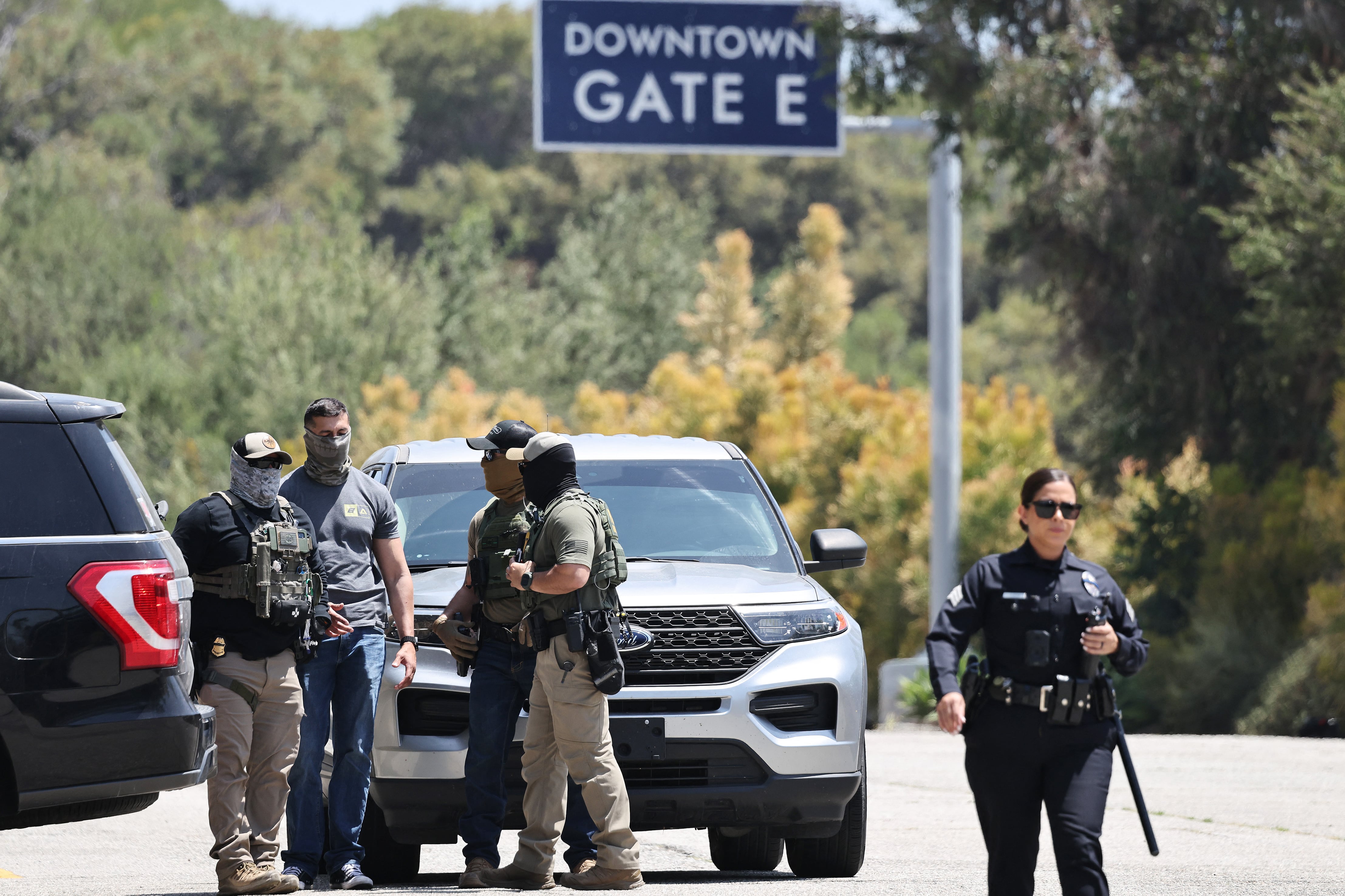 Una policía de Los Ángeles camina cerca de agentes federales enmascarados en la entrada del Dodger Stadium