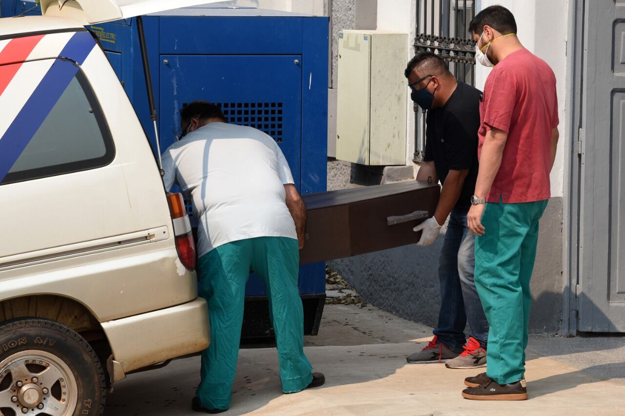 Empleados de la oficina forense cargan el cajón de una de las niñas en la morgue judicial.