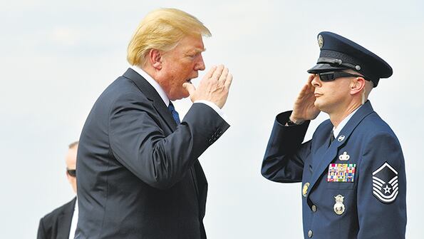 Trump saluda a un escolta en la base aérea Andrews antes de abordar el avión presidencial.