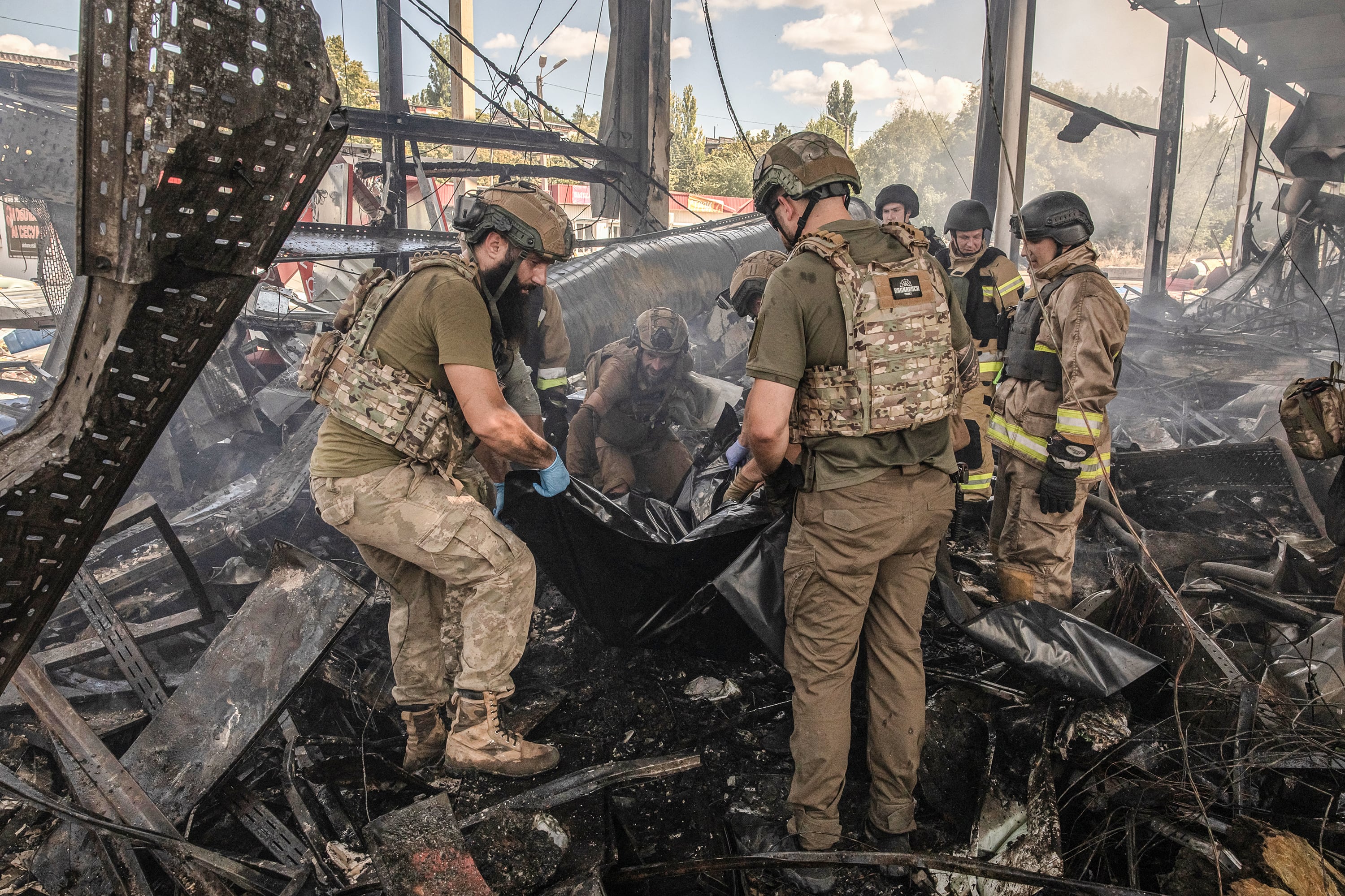 Remueven un cadáver delsupermercado bombardeado.