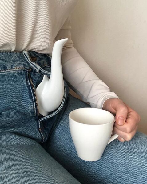 Refinamiento fálico, tetera y taza de té en mano en plan surrealista. 