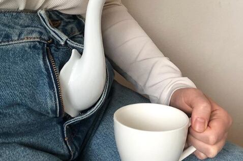 Refinamiento fálico, tetera y taza de té en mano en plan surrealista.