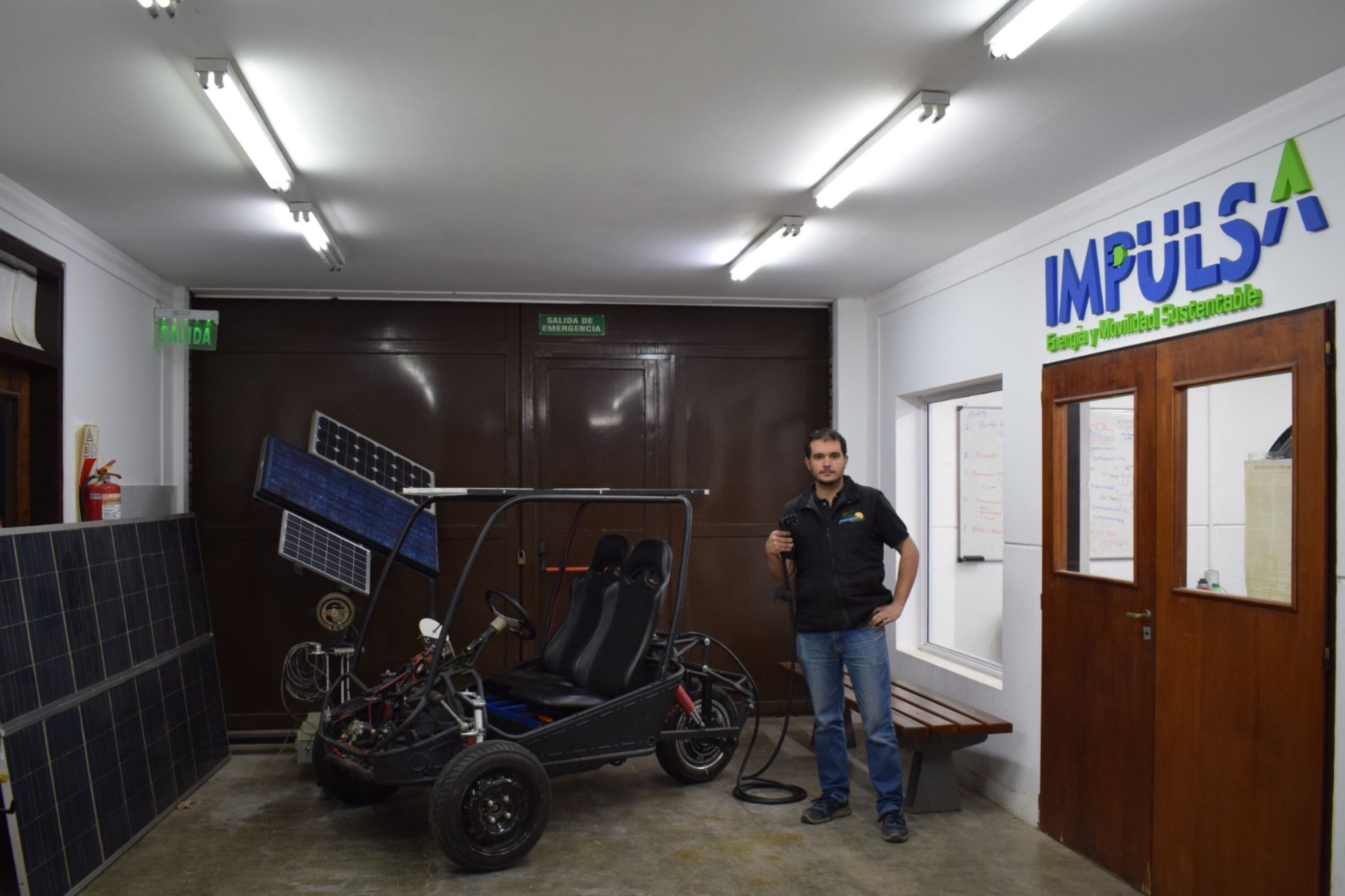 Nicolás Brizzio posa junto al vehículo biplaza en el Laboratorio de Electromovilidad.