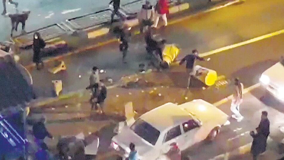 Un grupo de manifestantes patea barreras de tránsito el sábado a la noche en una calle de Teherán.