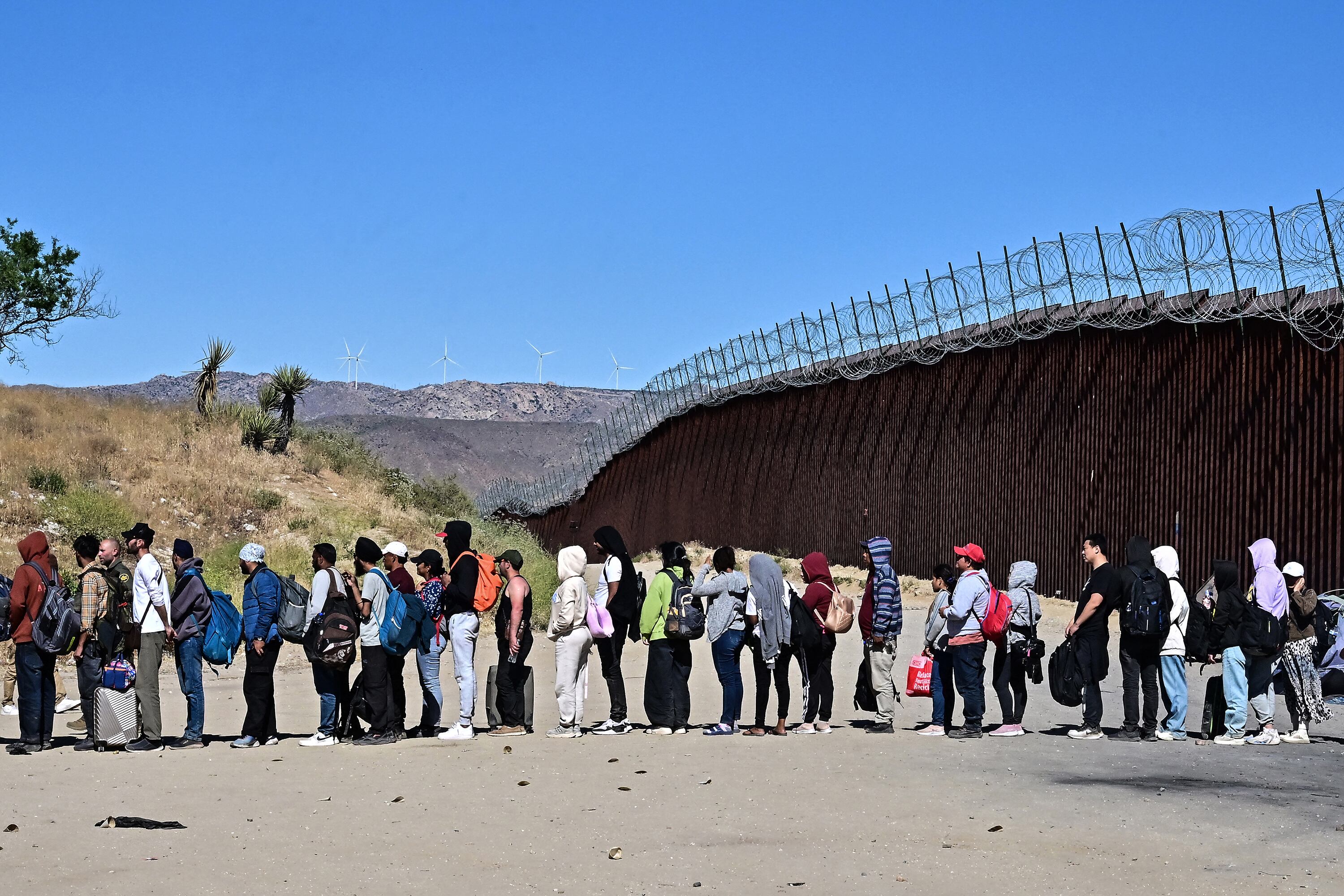 Migrantes en fila esperan para ser procesados en la frontera entre México y EE.UU.