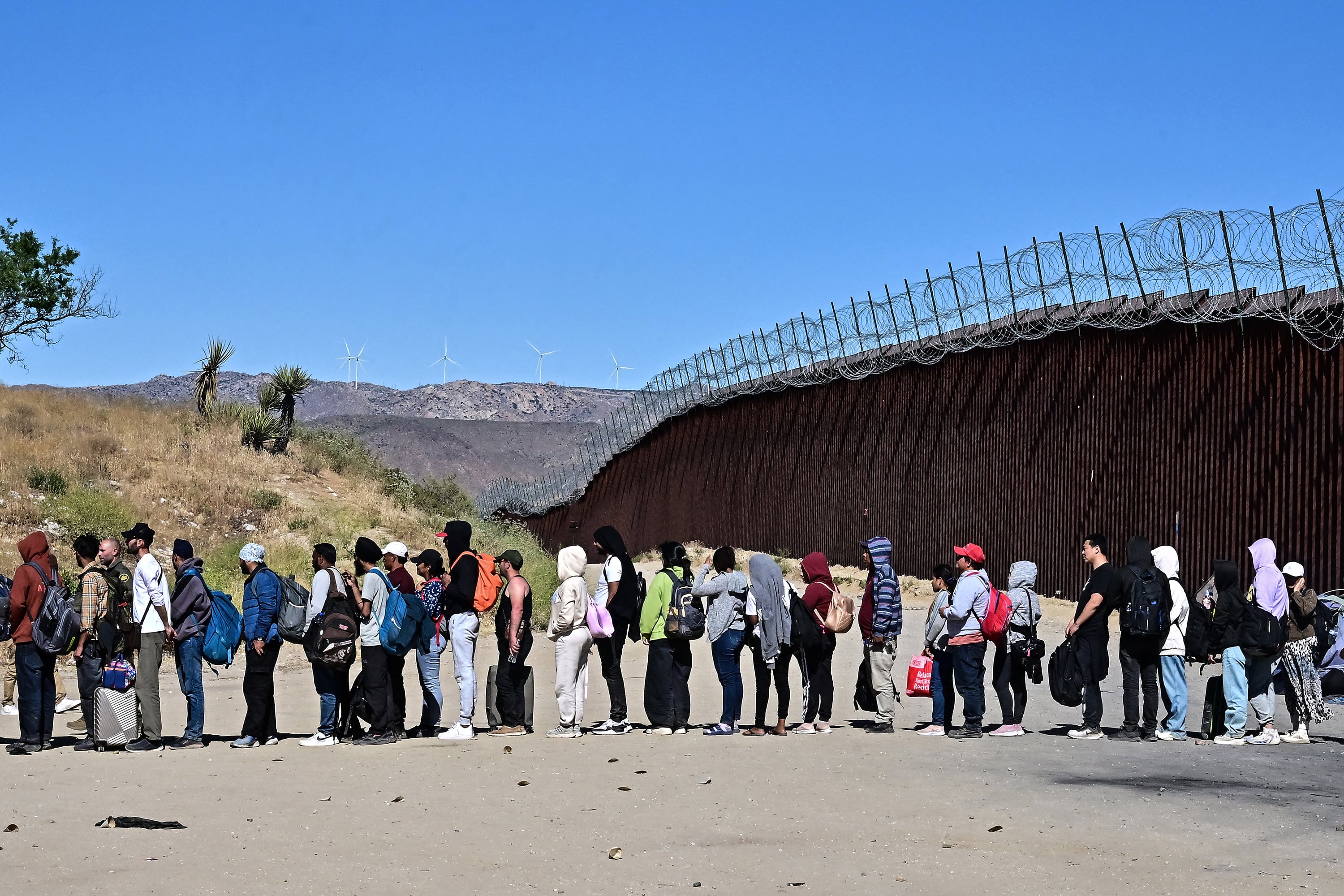 Migrantes en fila esperan para ser procesados en la frontera entre México y EE.UU.