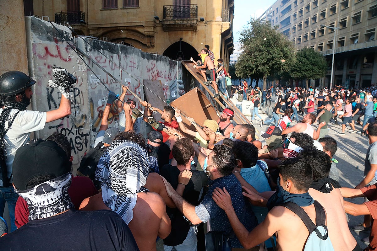 Manifestantes cargan contra una valla frente al Parlamento de Beirut.