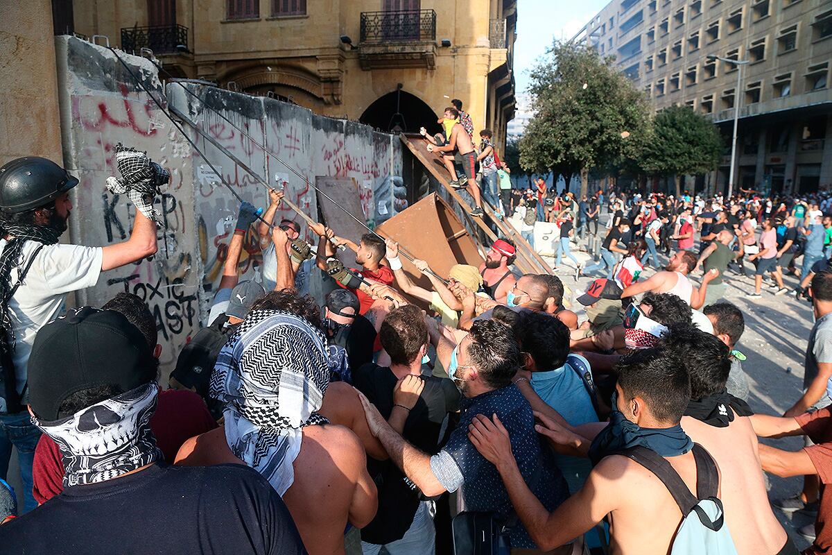 Manifestantes cargan contra una valla frente al Parlamento de Beirut.
