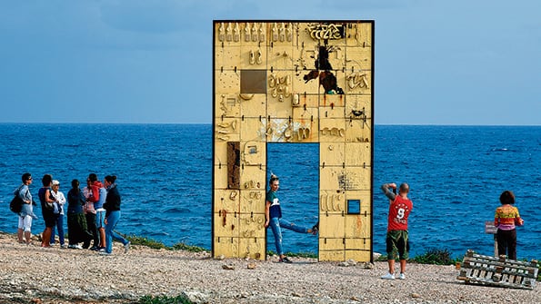Turistas sacan fotos en “La puerta de Europa”, un monumento a los migrantes.