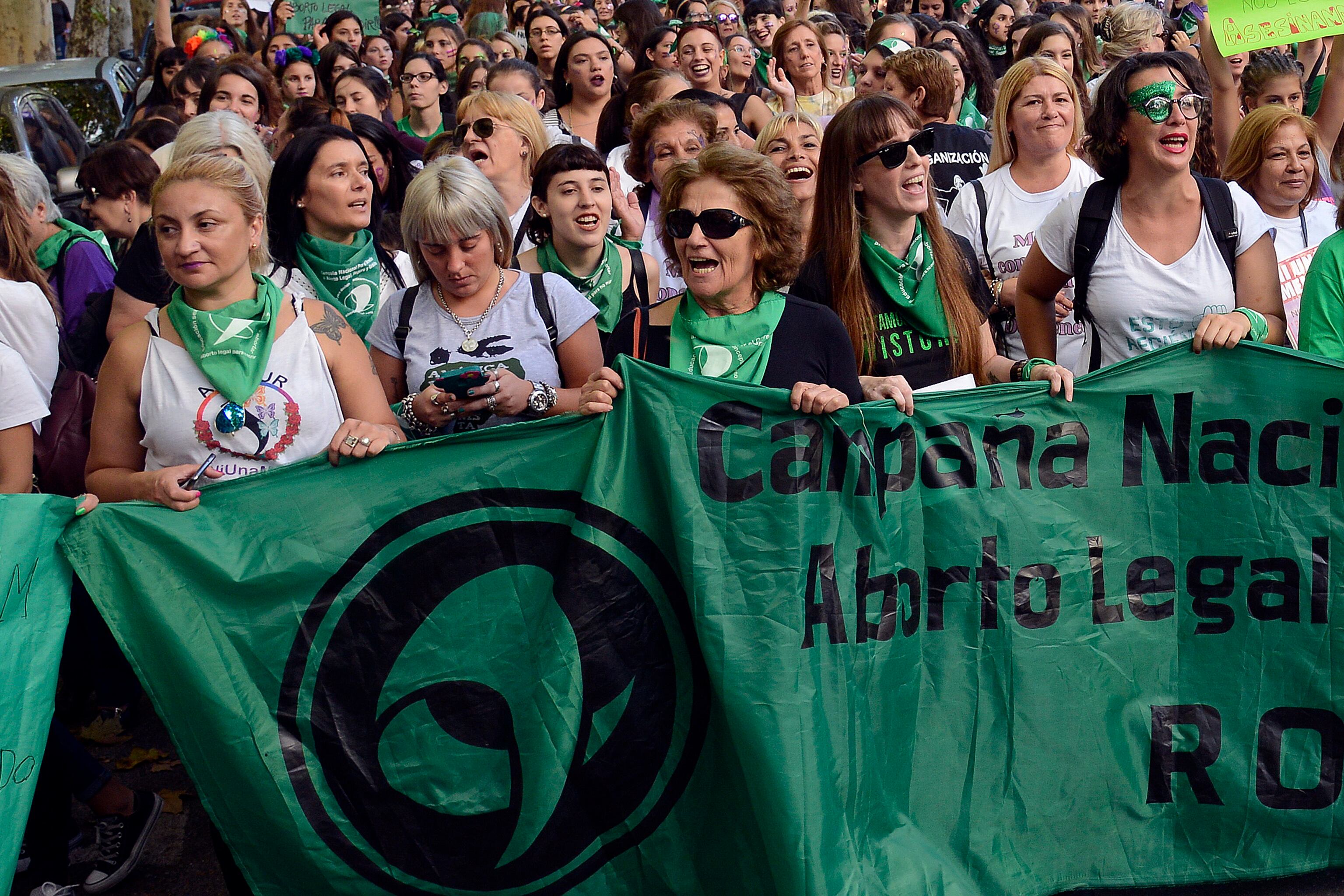 Mabel, con anteojos negros y pelo corto, al frente de la bandera de la Campaña por el Aborto Legal, Seguro y Gratuito.