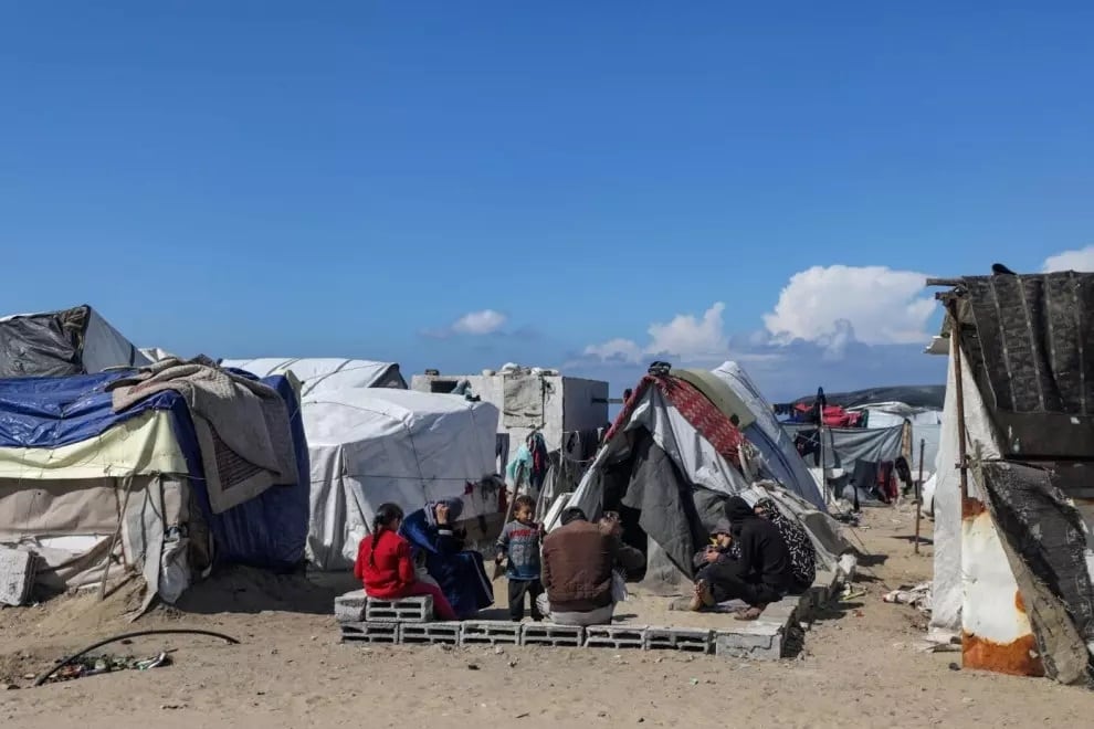 Una familia palestina desplazada de Rafah sentada frente a su refugio en Deir Al Balah, en el sur de la Franja de Gaza